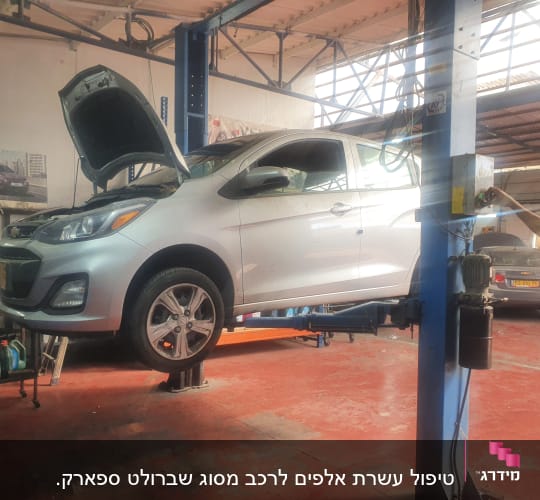 רכב על מעלית במוסך עם מכסה מנוע פתוח